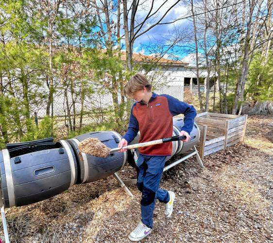 Merrick Chapin, an 11th grader shovels dried leaves to add to the composters at the Hopkinton High Middle School