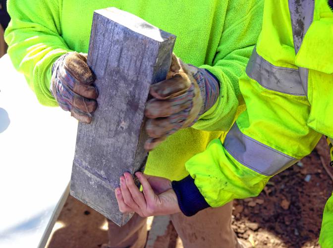 Members of the S&R Demolition team out of Lowell, Massachusetts look over the time capsule as they retrieve it from the building on Tuesday morning.