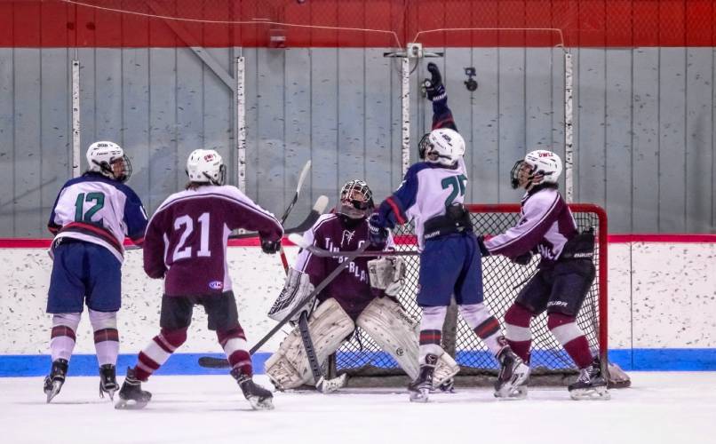 Forward Owen Buss tries to swat the puck out of midair in front of goal during the first period of John Stark-Hopkinton-Hillsboro/Deering’s boys’ hockey game with Timberline on Wednesday night at New England College in Henniker. Buss is one off the Hopkinton High members on the three-school cooperative team.