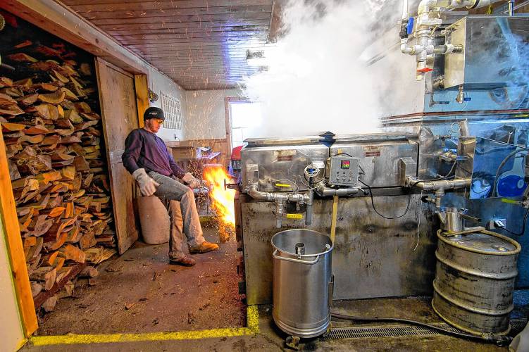 Jeff Moore of Windswept Farm in Loudon uses his foot to close the door of the wood-fired evaporator at their maple processing building. 
