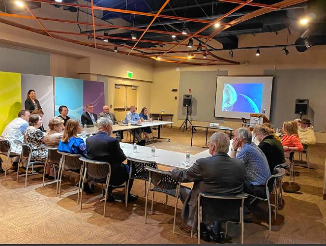 Astronaut Christina Koch, in blue NASA jacket with back to camera, between U.S. Sen. Jeanne Shaheen and Concord Mayor Byron Champlin during a roundtable discussion concerning the Artemis return-to-moon project, held at the McAuliffe-Shepard Discovery Center, May 6, 2024.