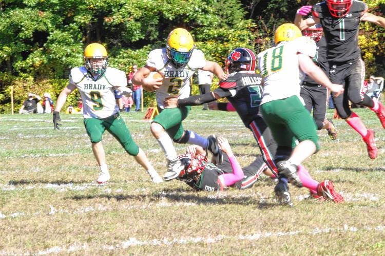 Bishop Brady running back Ian Miller (2) avoids tackles by Hillsboro-Deering's Andrew Abair (22) and Ethan Franklin (12) during the fourth quarter of H-D's first ever homecoming football game on its campus on Saturday, Oct. 5, 2024. Miller ran for two touchdowns and caught another in his first game back from injury. 