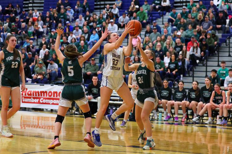 Lilli Carlile (33) splits between Pembroke's Anne Phillips (5) and Taylor Renna as she drives to the basket during the Division II girls’ basketball championship at UNH on Sunday, March 10. Carlile, a First Team All-State selection, set a D-II championship record, scoring 29 points to lead the Kingsmen to the championship. 