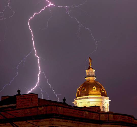 Lightning strikes near the east side of the New Hampshire State House as a front moved through the area on Tuesday night, July 16, 2024. The roof of the State Library is in the foreground.